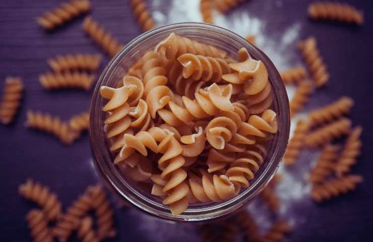 pasta integrale in un bicchiere e sul tavolo